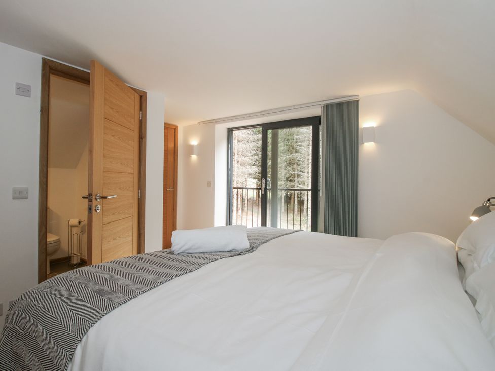 A bedroom with a bed and curtains at The Barn in Acton near Bishop's Castle