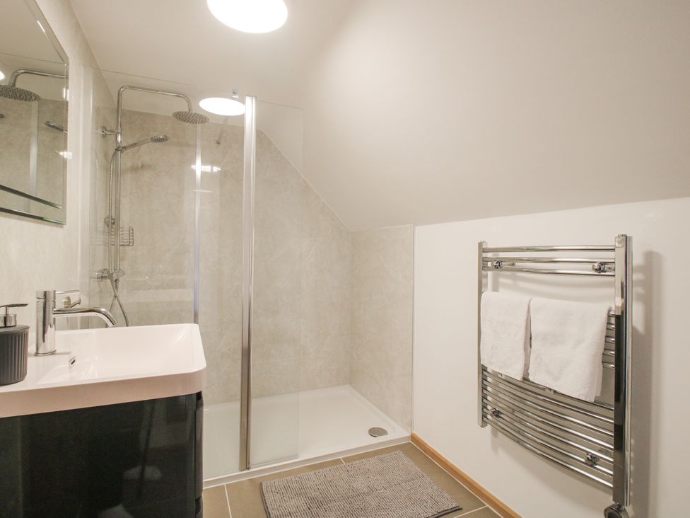 A bathroom with a shower, sink, and towel warmer at The Barn in Acton near Bishop's Castle