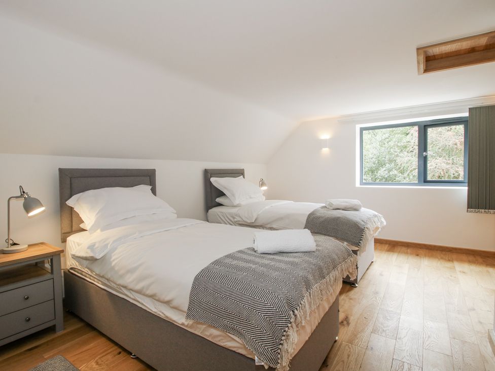 A bedroom with two beds and a window at The Barn in Acton near Bishop's Castle