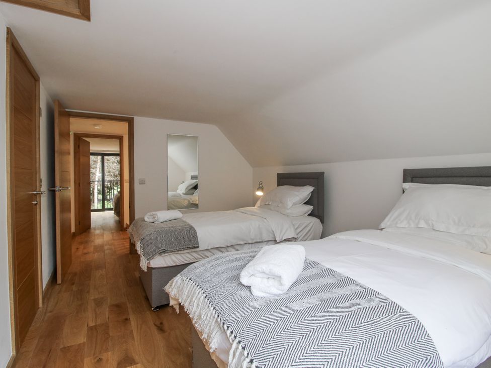 A bedroom with two beds and a mirror at The Barn in Acton near Bishop's Castle