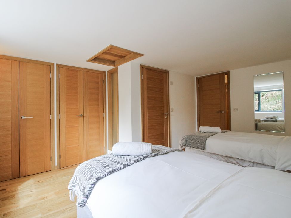 A bedroom with two beds and wooden doors at The Barn in Acton near Bishop's Castle