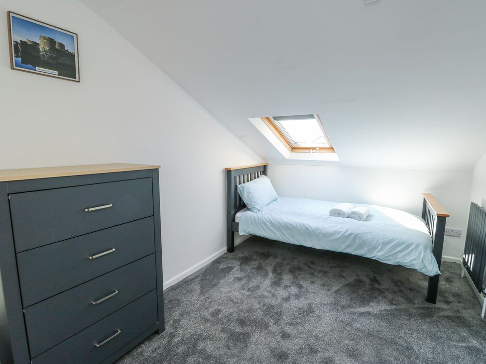 A bedroom with a single bed under a skylight window and a chest of drawers on the side at Ty Copr in Amlwch
