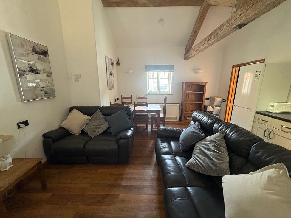 A living room with a sofa and dining table at Woodside Cottage in Kerry