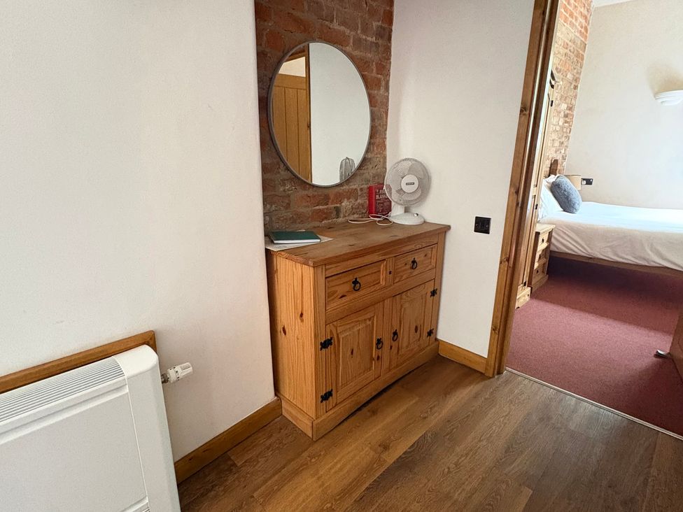 A dresser with a mirror in a bedroom at Woodside Cottage in Kerry