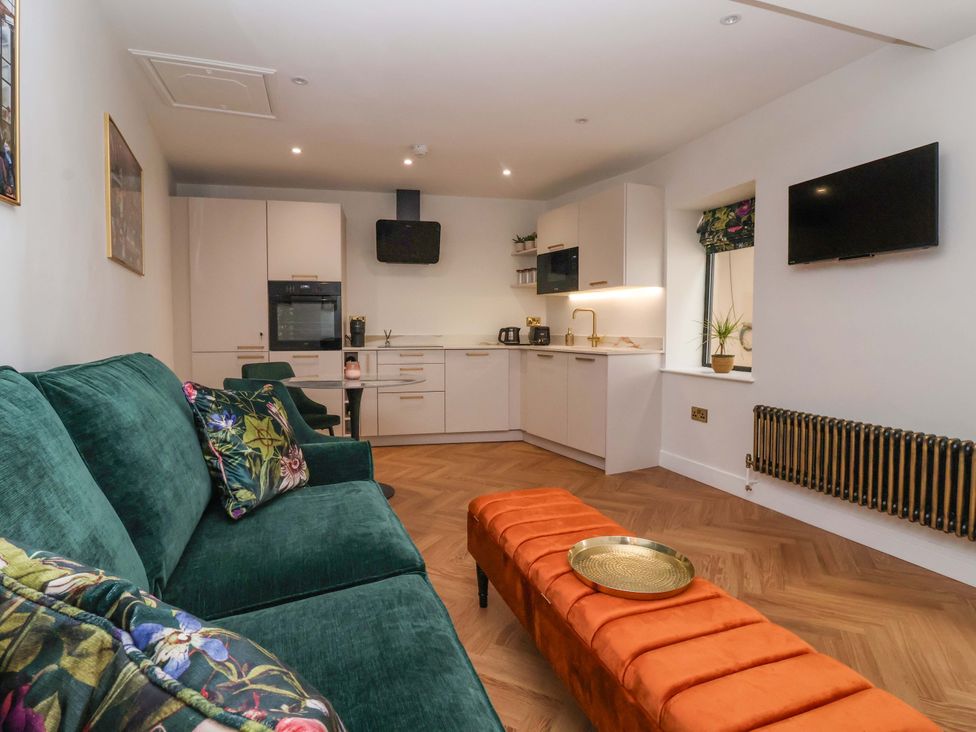 A living room with a sofa and kitchen appliances at The Old Bakehouse 