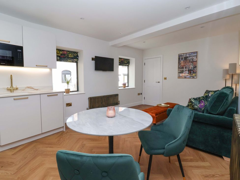 A living room with a kitchen area and seating at The Old Bakehouse 