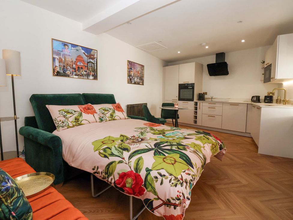 A studio apartment with a sofa bed and kitchen unit at The Old Bakehouse in 