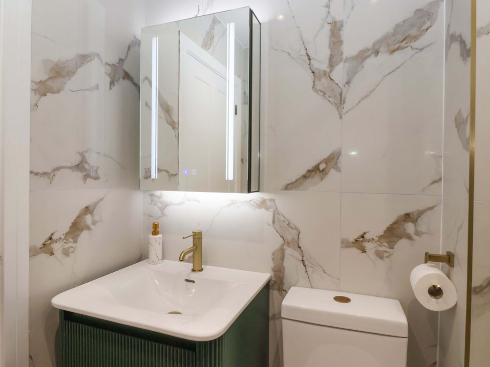 A bathroom with a sink, toilet, and mirror at The Old Bakehouse 