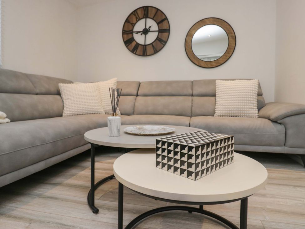 A living room with a sofa, coffee table, and decorative items at Cosy Corner in White Cross Bay near Troutbeck Bridge