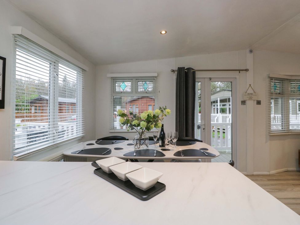A dining room with a table and chairs at Cosy Corner White Cross Bay near Troutbeck Bridge