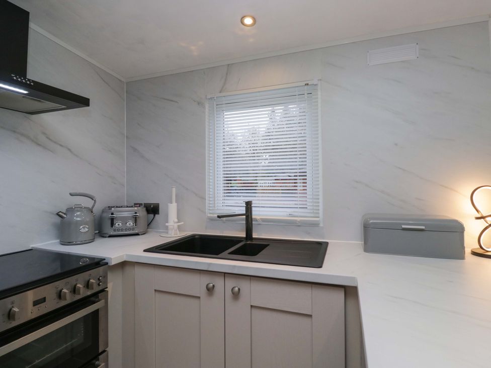 A kitchen with a sink and stove at Cosy Corner in White Cross Bay near Troutbeck Bridge