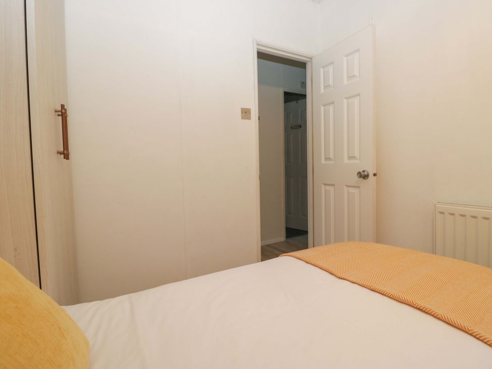 A bedroom with a bed and wardrobe at Cosy Corner White Cross Bay near Troutbeck Bridge