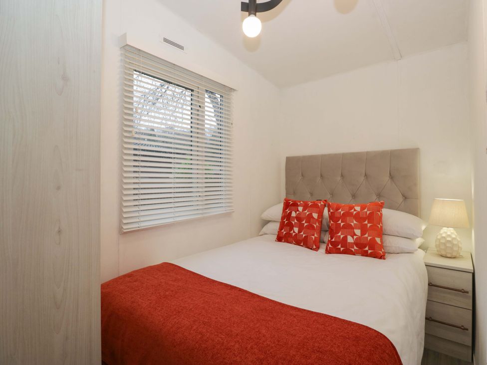 A bedroom with a bed and nightstand at Cosy Corner White Cross Bay near Troutbeck Bridge