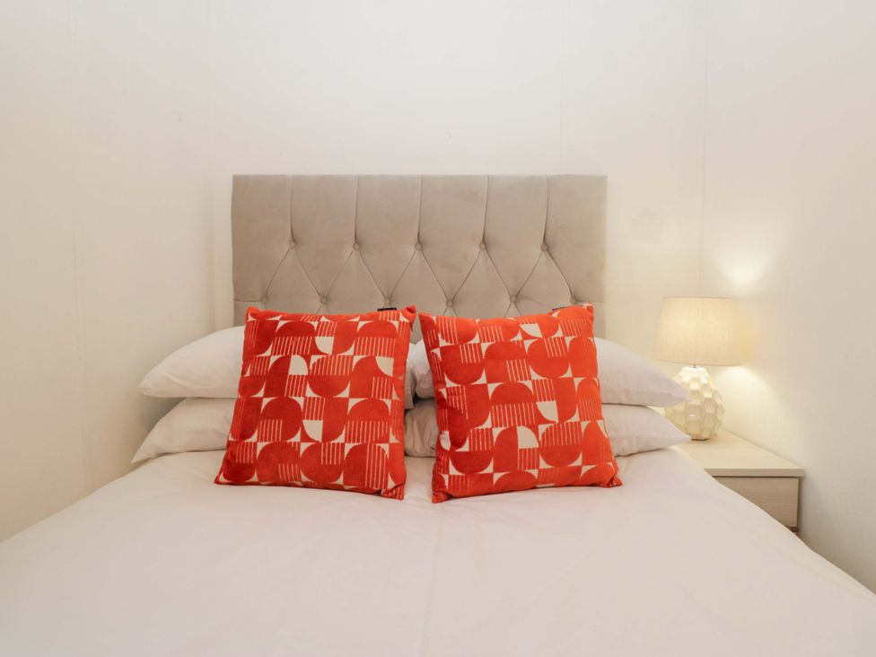 A bedroom with a bed and patterned pillows at Cosy Corner White Cross Bay near Troutbeck Bridge