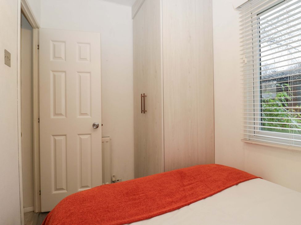 A bedroom with a bed and wardrobe at Cosy Corner in White Cross Bay near Troutbeck Bridge