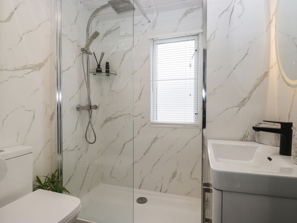 A bathroom with a shower, toilet, and sink at Cosy Corner White Cross Bay near Troutbeck Bridge