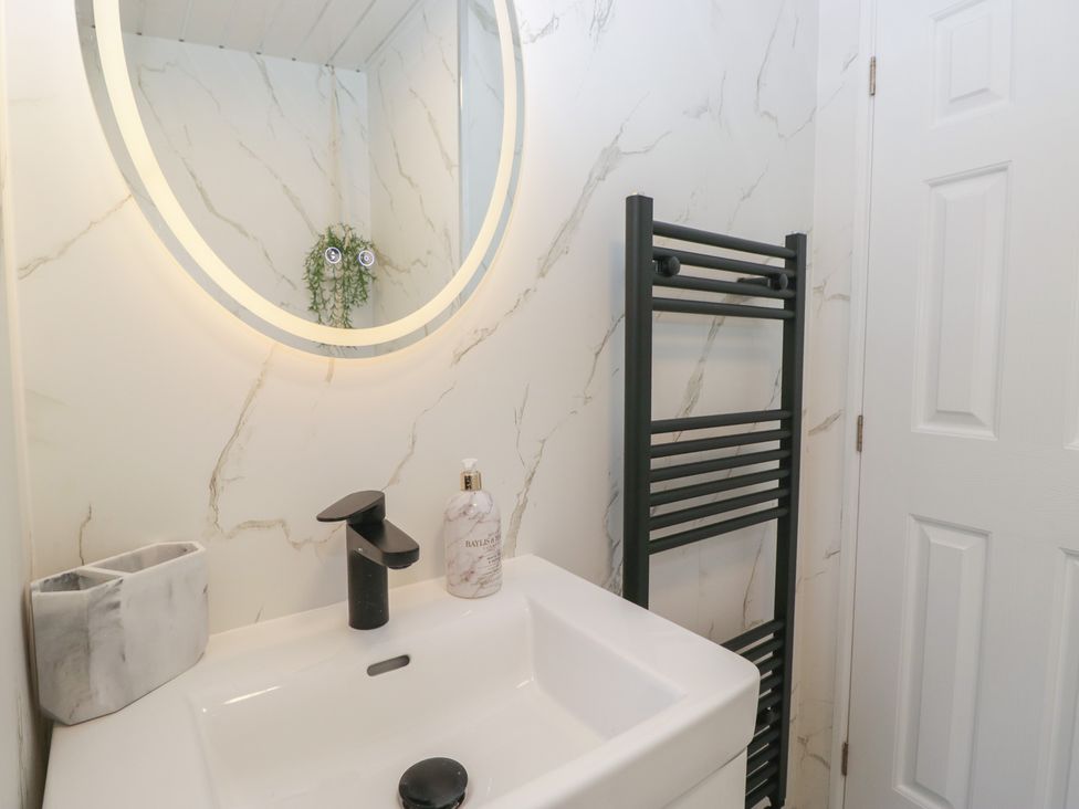 A bathroom with a sink, mirror, and towel rail at Cosy Corner near White Cross Bay