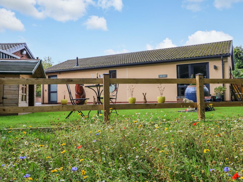 A house with a flower bed and a table in the garden at The Nest in Wetheral