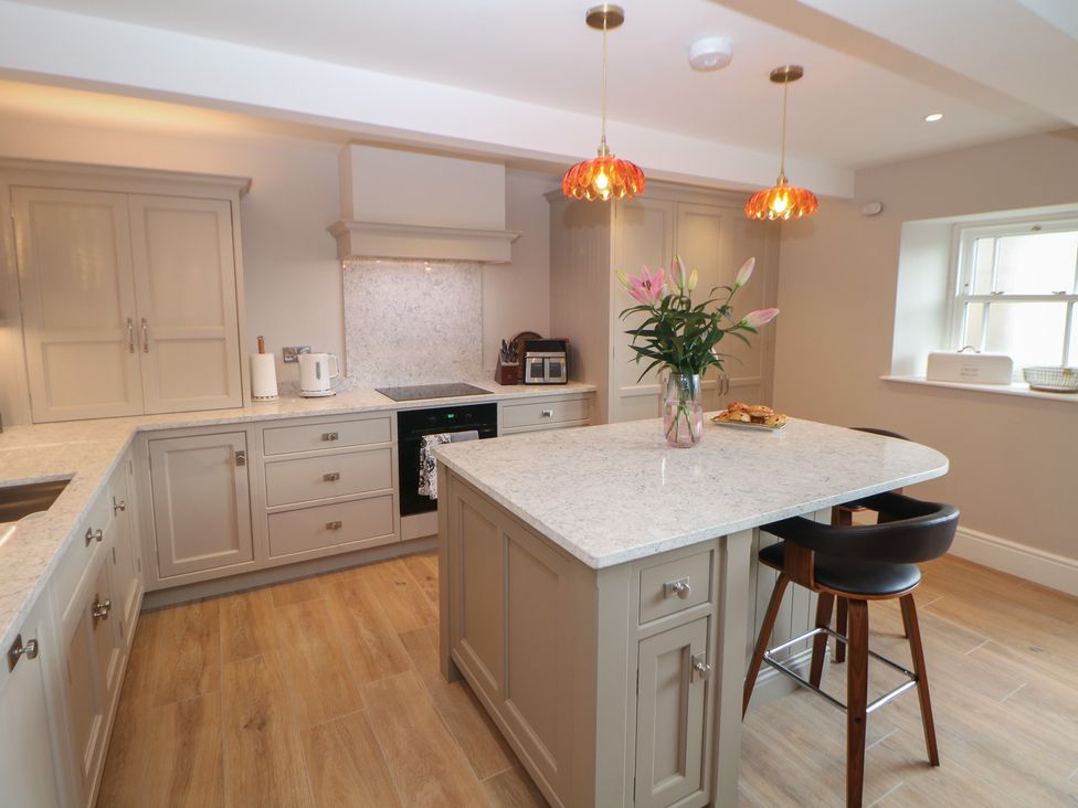 A kitchen with a kitchen island and flowers at Coach House Matlock