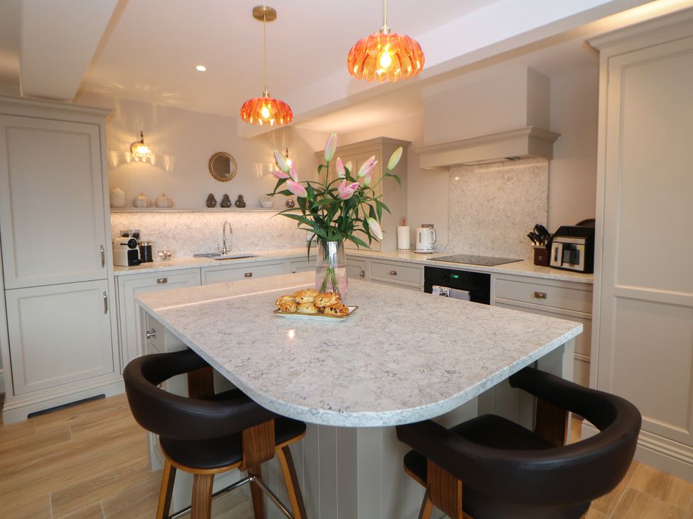 A kitchen with an island and flowers in a vase at Coach House in Matlock