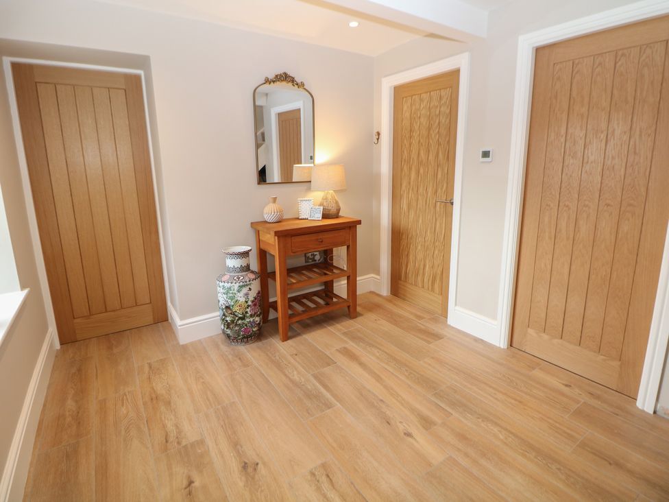 A hallway with a table, lamp, and vase at Coach House in Matlock