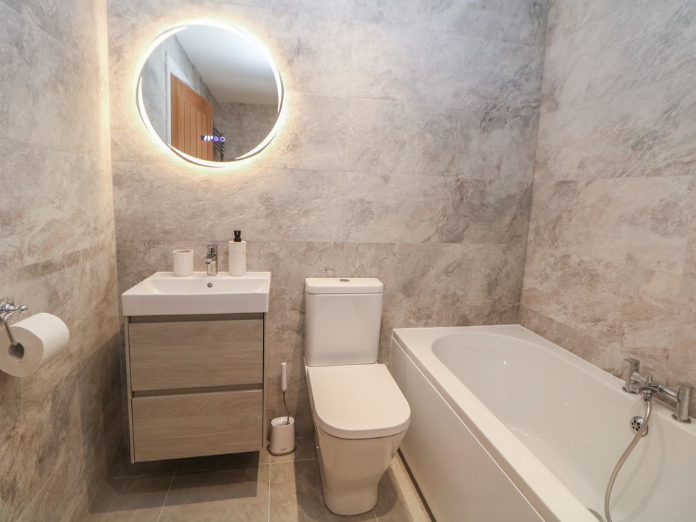 A bathroom with a bathtub and a toilet at Coach House in Matlock