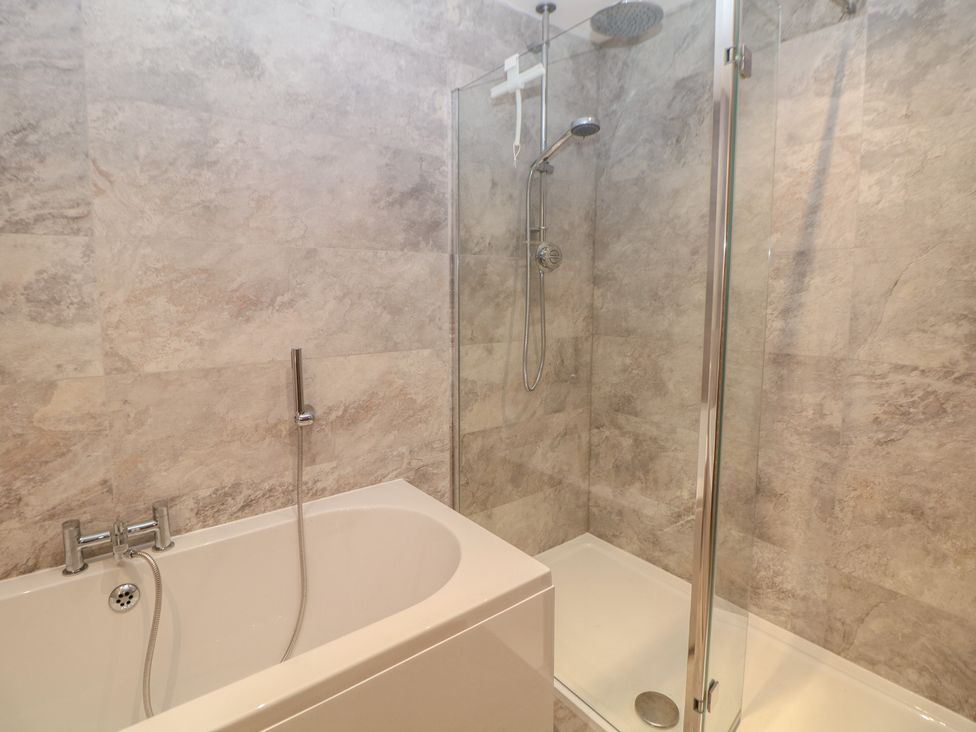 A bathroom with a bathtub and shower at Coach House in Matlock
