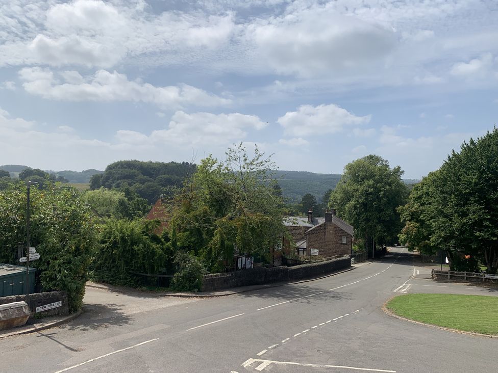 A view of houses and trees along a road with hills in the background at The Coach House in Holloway