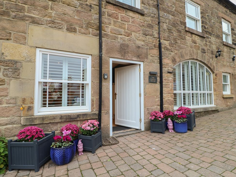 An outdoor entrance with a white door and flower planters at The Coach House in Holloway