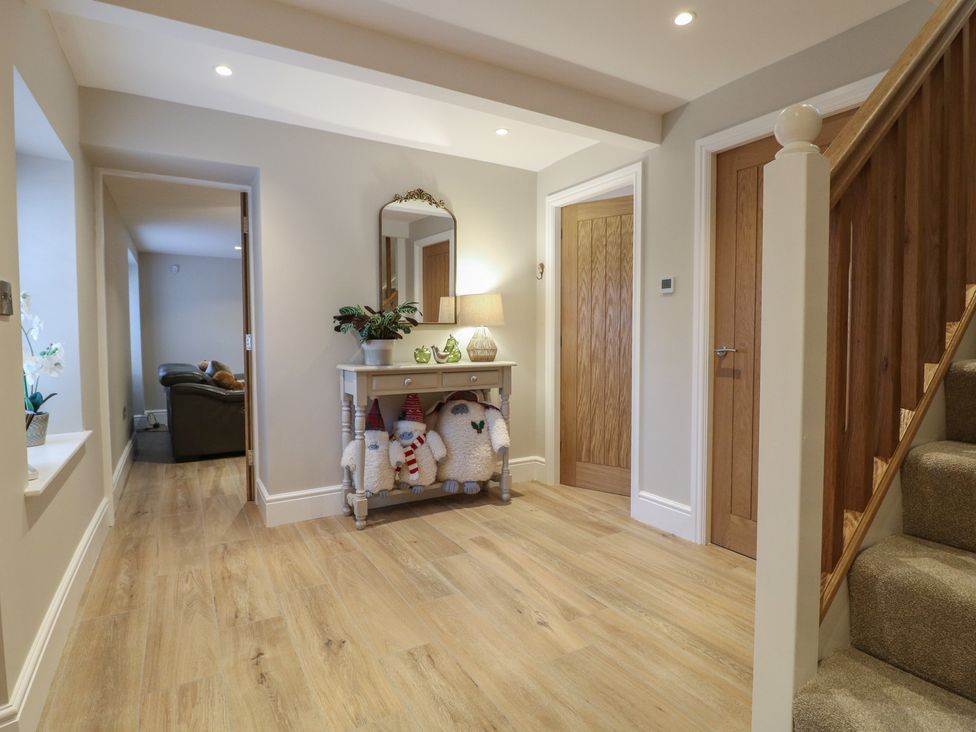 A hallway with a table, lamp, and mirror at The Coach House in Holloway