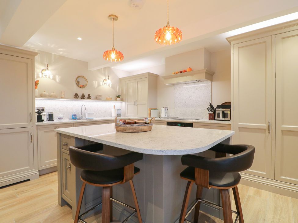A kitchen with a marble countertop and bar stools at The Coach House in Holloway