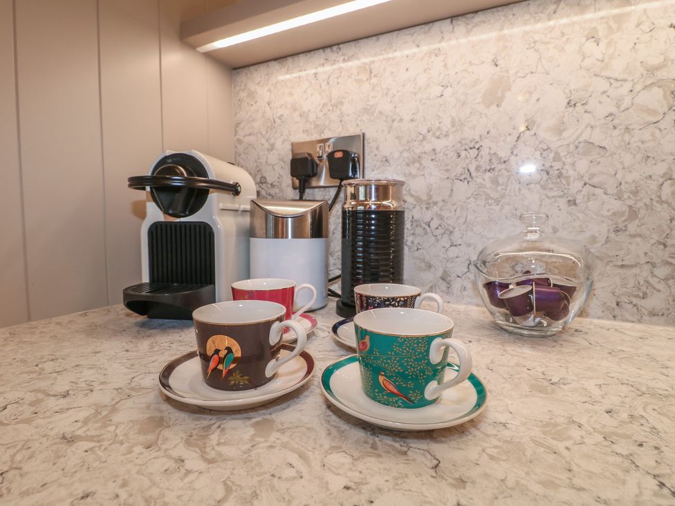 A kitchen counter with a coffee machine and cups at The Coach House in Holloway
