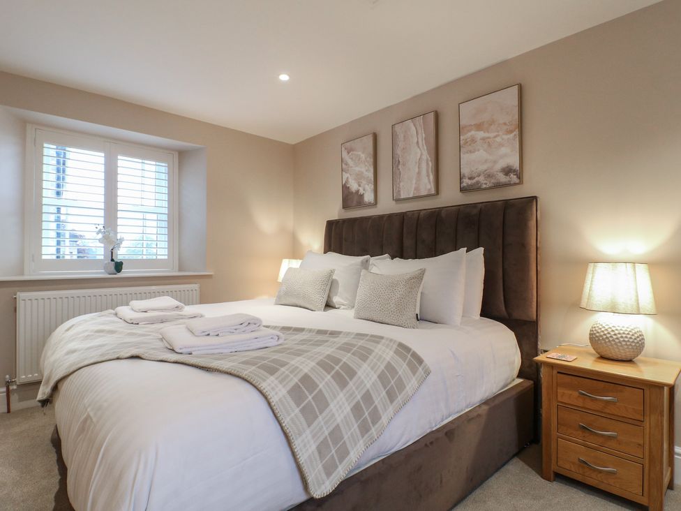 A bedroom with a bed and bedside table at The Coach House in Holloway