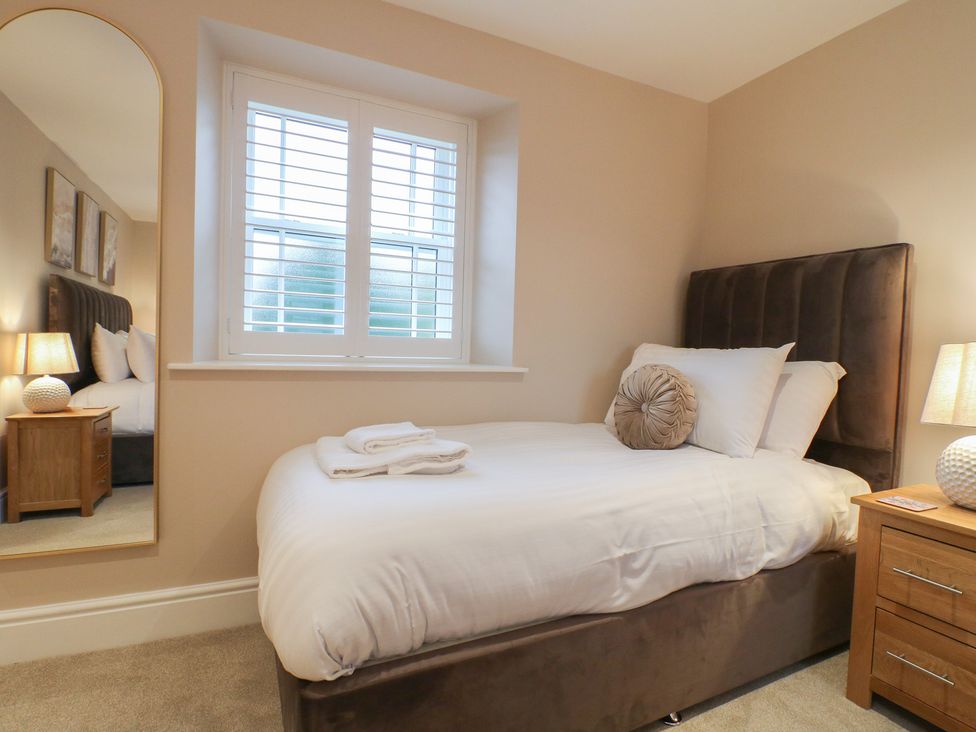 A bedroom with a bed and nightstand at The Coach House in Holloway