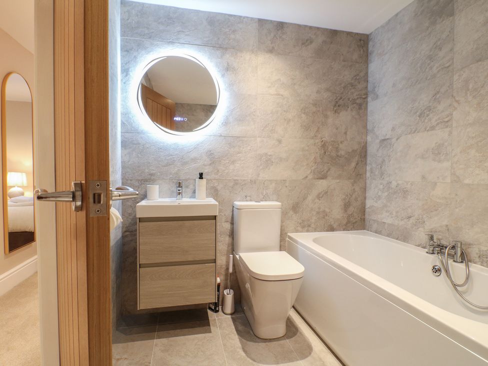 A bathroom with a bathtub and vanity unit at The Coach House in Holloway