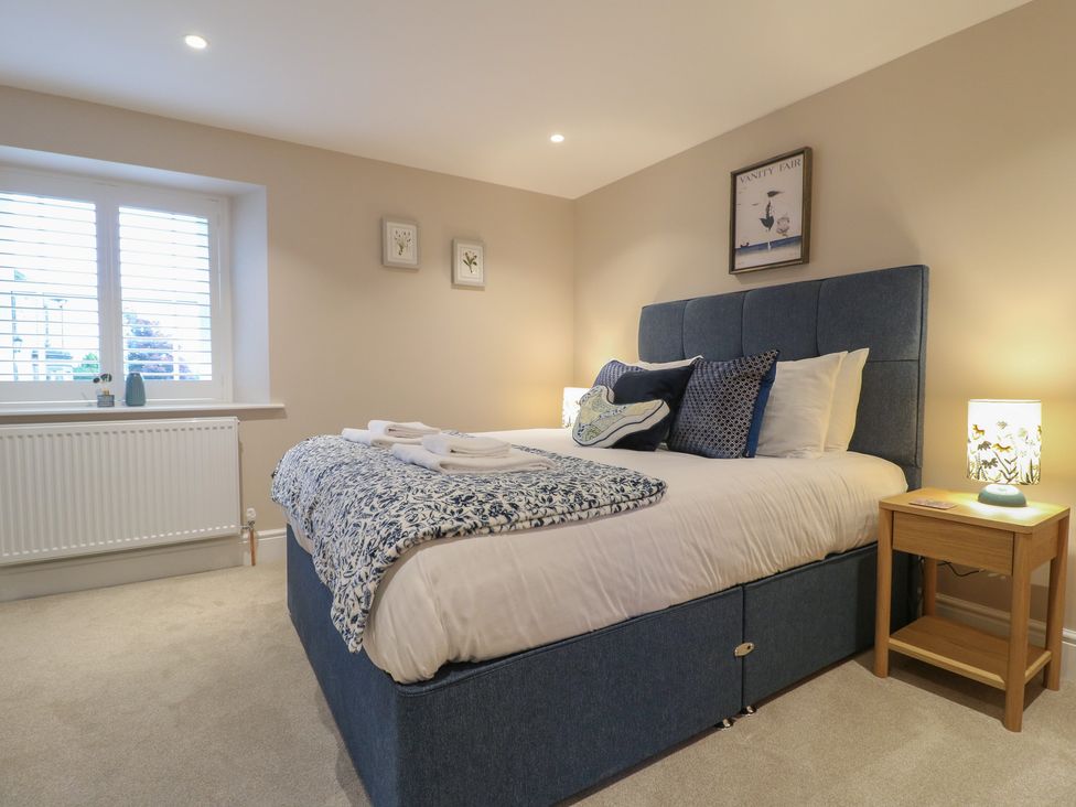 A bedroom with a bed and nightstand at The Coach House in Holloway