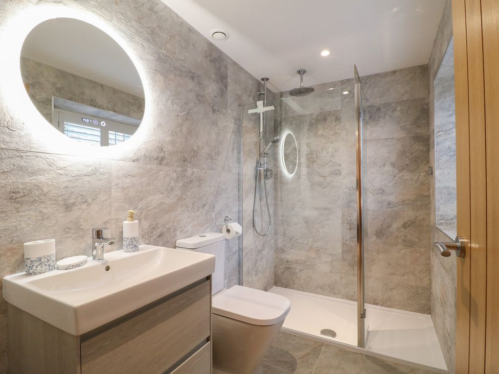 A bathroom with a shower, toilet, and sink at The Coach House in Holloway