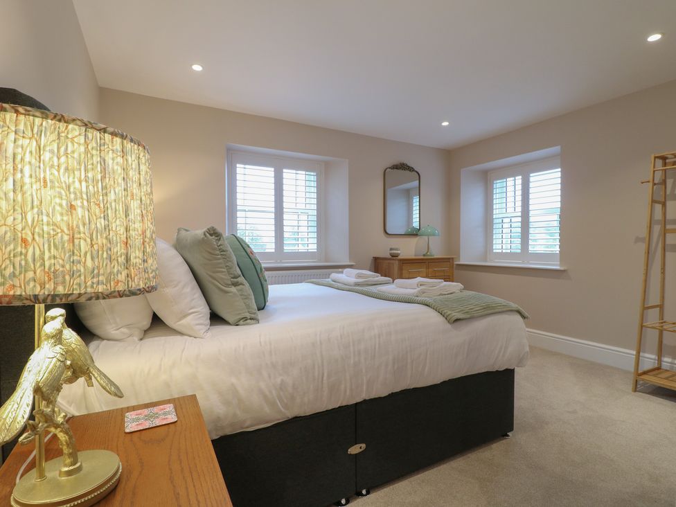 A bedroom with a bed and lamp at The Coach House in Holloway