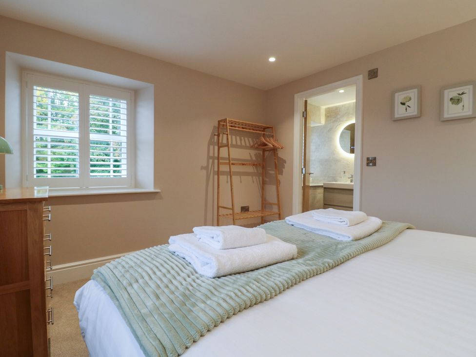 A bedroom with a bed and a hanging rack at The Coach House in Holloway
