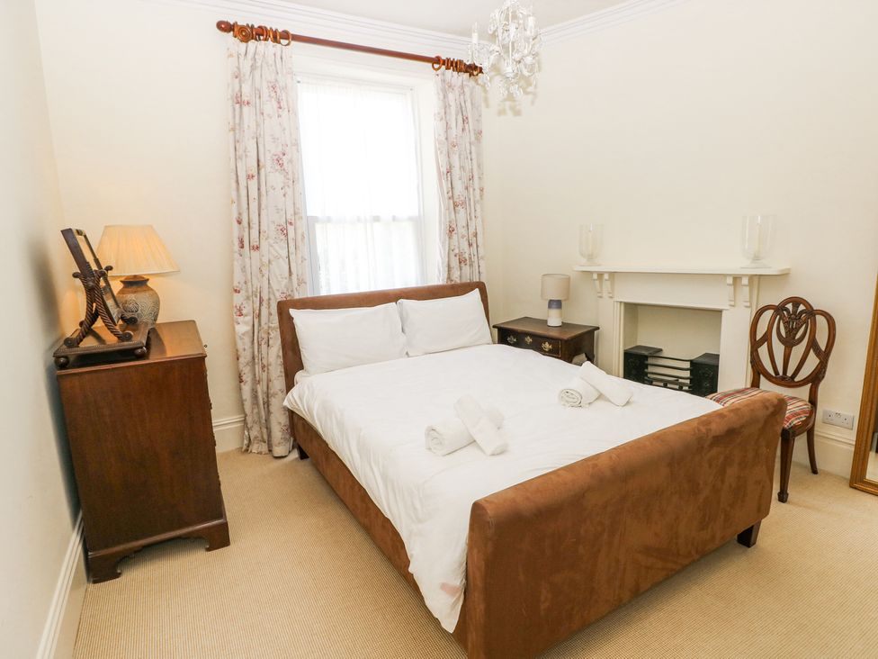 A bedroom with a double bed next to a window with floral curtains at Hereford House in Tenby