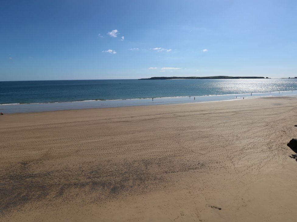 A wide sandy beach with few people near the water and an island in the distance at Hereford House in Tenby