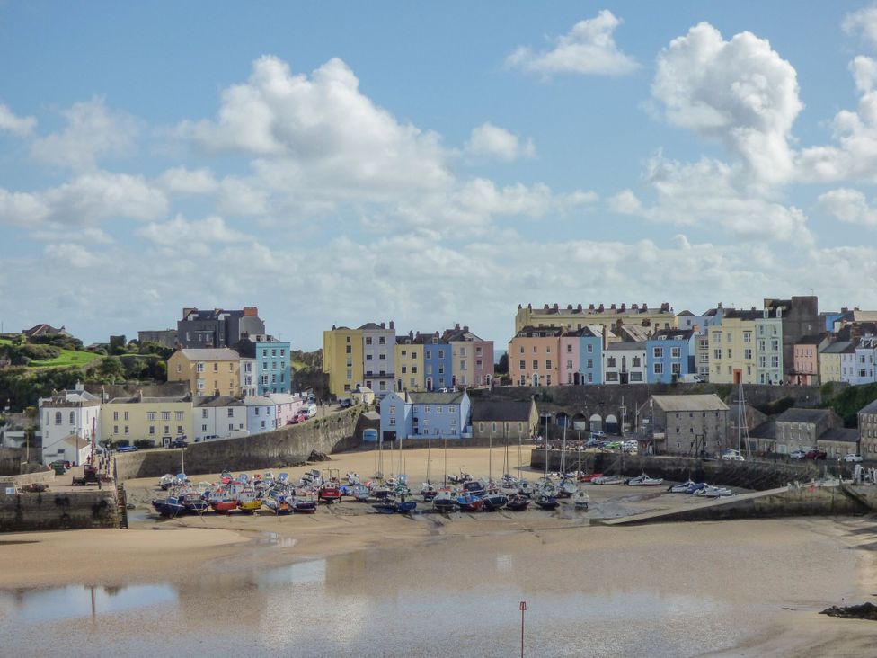 A harbor with boats on sand and colorful buildings in the background at Hereford House in Tenby