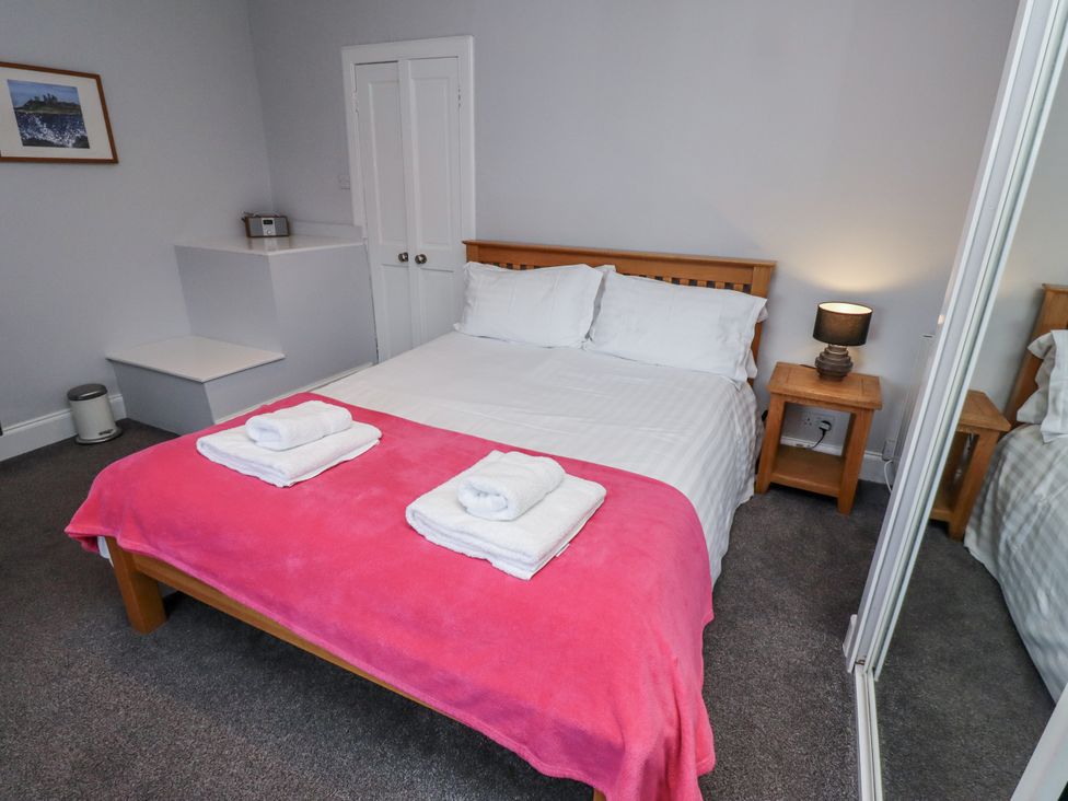 A bedroom with a bed and towels at Kennie Cottage in Seahouses