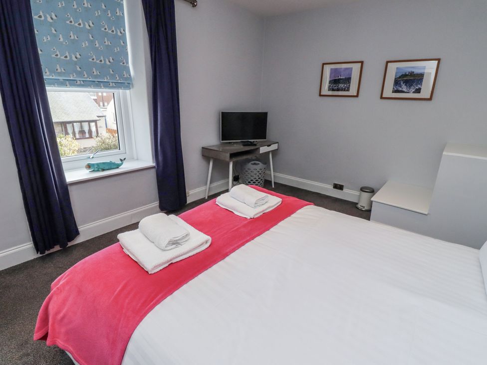 A bedroom with a bed and television at Kennie Cottage in Seahouses