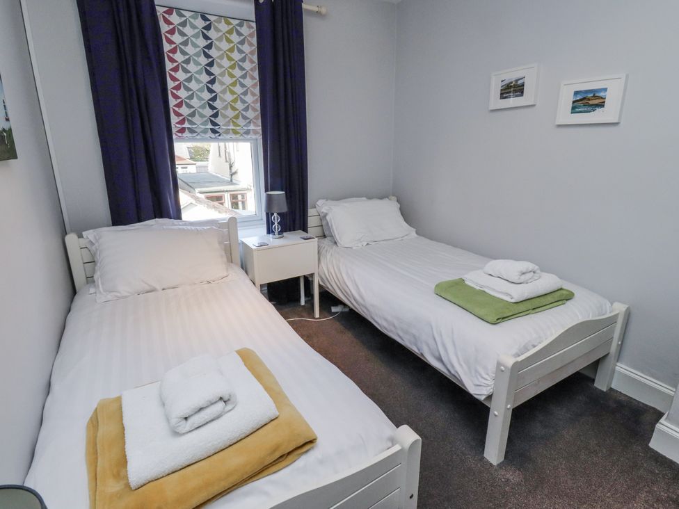 A bedroom with two beds and a nightstand at Kennie Cottage in Seahouses
