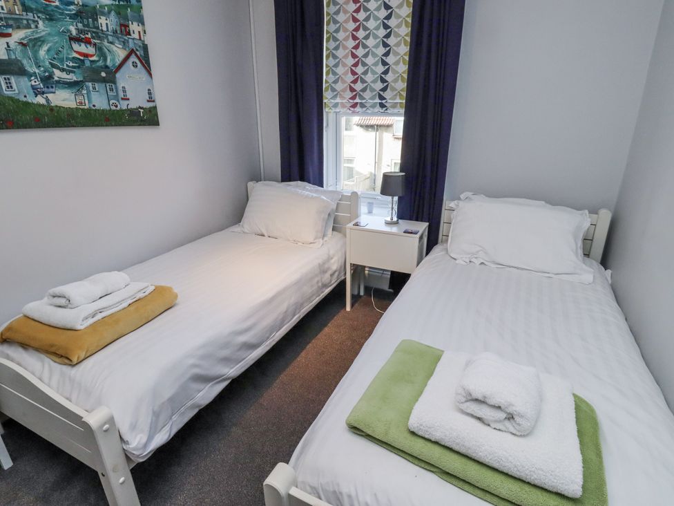 A bedroom with two single beds and a bedside table at Kennie Cottage, Seahouses