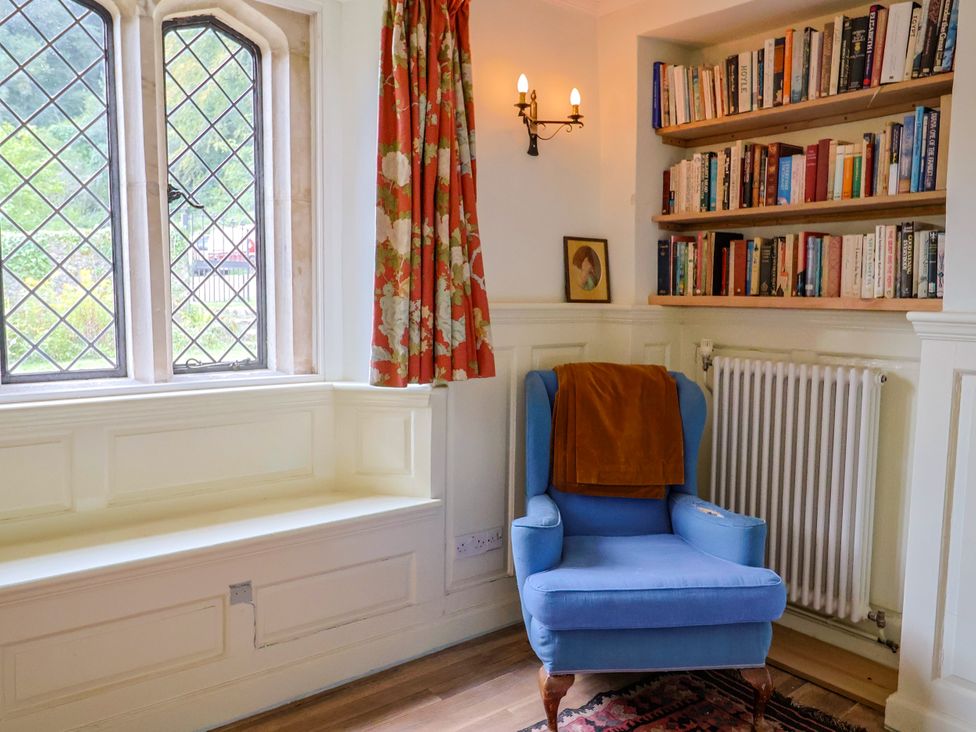 A snug with a blue armchair and a bookshelf at Hole House in Branscombe