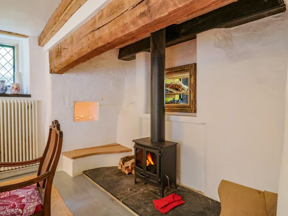 A living room with a fireplace and a chair at Hole House in Branscombe