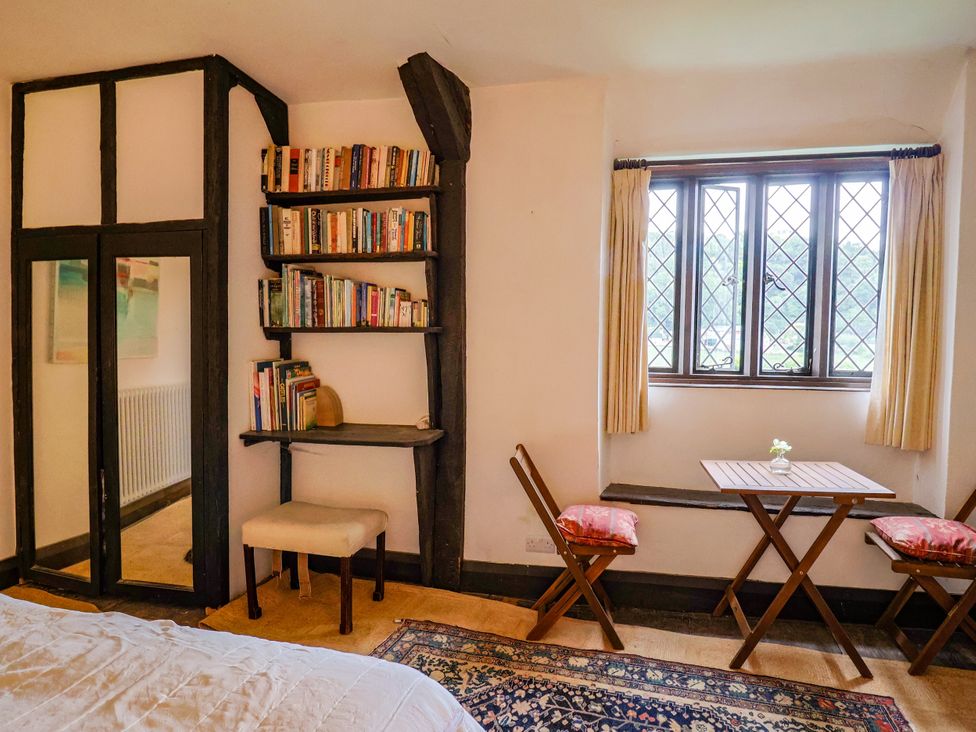 A bedroom with a bookshelf and a small table at Hole House in Branscombe