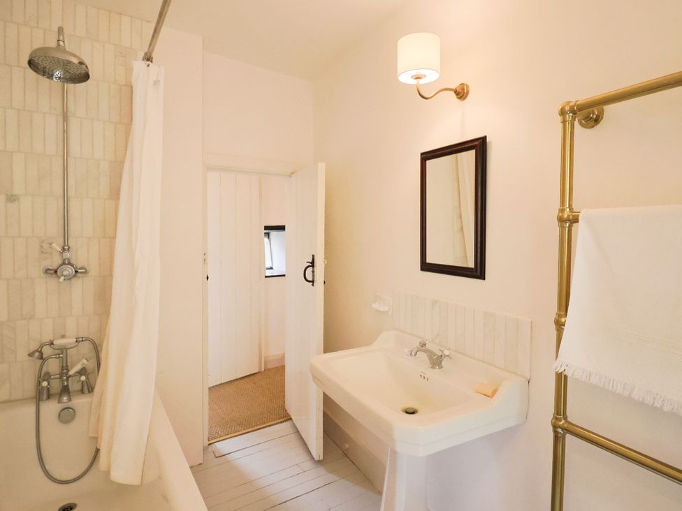 A bathroom with a bathtub and washbasin at Hole House in Branscombe